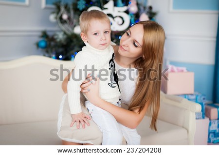 Mom sits with a boy in her arms near a Christmas tree