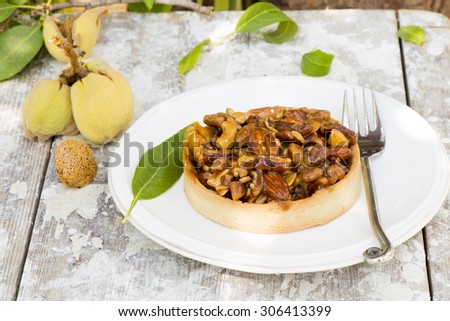 nuts, almonds  and caramel tart, on a rustic background in the almond orchard