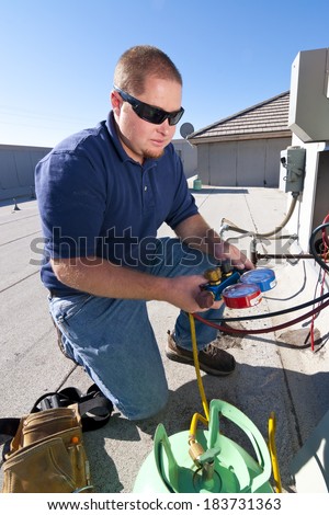 Repair technician on rooftop with testing equipment fixing HVAC System