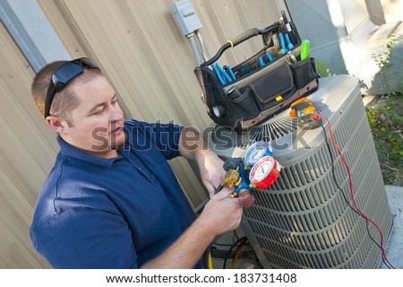 Air Conditioner Repair Man. Using testing equipment on outside unit.