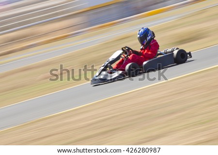 Youth Go Kart Racer on track.  Shot is panned to emphasize speed.