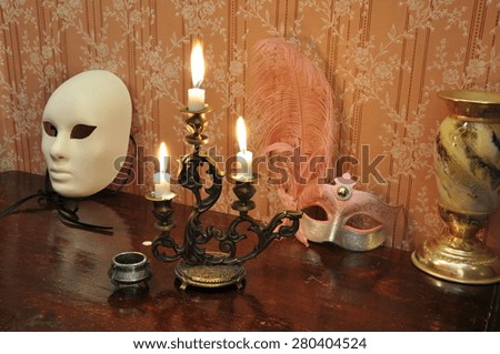 Elegant still life with  bronze candelabra, antique goblet and two masks on an old wallpaper background