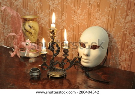 Elegant still life with  bronze candelabra, antique goblet and two masks on an old wallpaper background