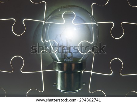 Illuminated light bulb on top of a jigsaw puzzle