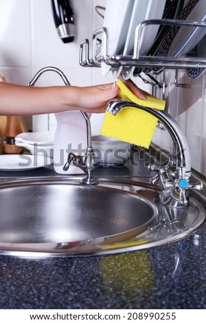 Cleaning the kitchen sink with sponge