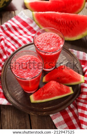 Watermelon smoothies with sliced fruit on brown wooden background