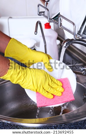 Male hand in gloves with sponge washing dish