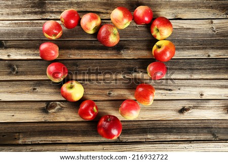 Heart of apples on brown wooden background