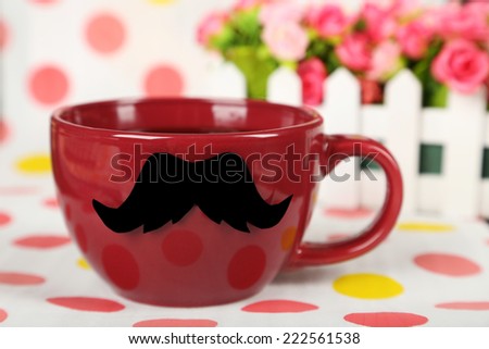 Red cup with paper mustache on colorful background