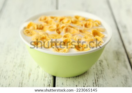 Bowl of cornflakes with milk on white wooden background