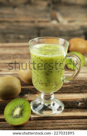 Fresh kiwi smoothie in glass on brown wooden background