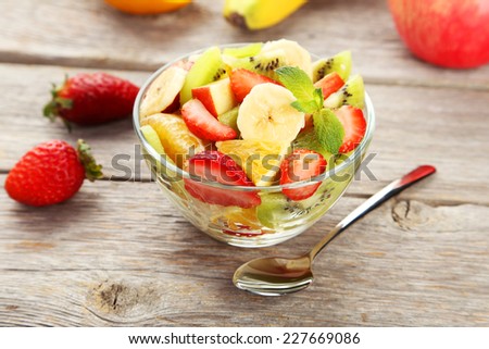 Fresh fruit salad in bowl on grey wooden background