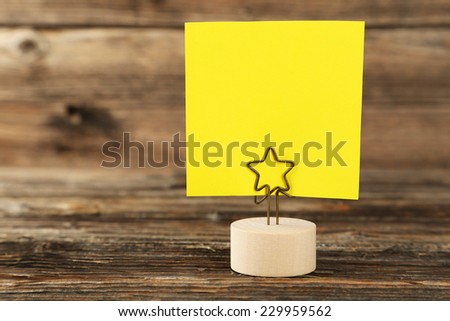 Yellow note paper on a holder on brown wooden background