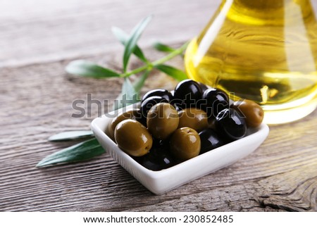 Green and black olives in bowl on grey wooden background