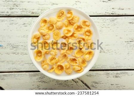 Bowl of cornflakes with milk on white wooden background