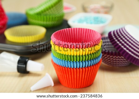 Empty colorful cupcake cases on wooden background