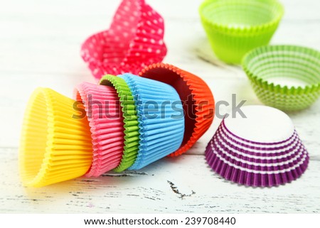 Empty colorful cupcake cases on white wooden background