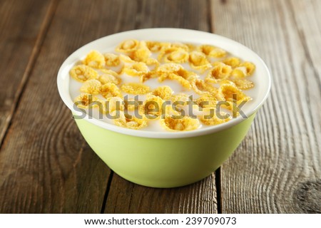 Bowl of cornflakes with milk on brown wooden background