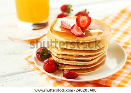 Delicious pancakes with strawberry on white wooden background