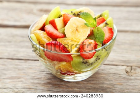 Fresh fruit salad in bowl on grey wooden background