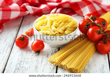 Spaghetti with bowl of pasta and tomatoes on white wooden background