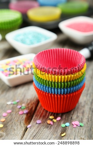 Empty colorful cupcake cases on grey wooden background
