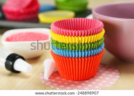 Empty colorful cupcake cases on wooden background