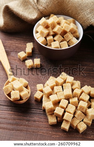 Brown sugar in spoon and bowl on brown wooden background