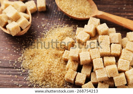 Brown sugar in spoon on brown wooden background