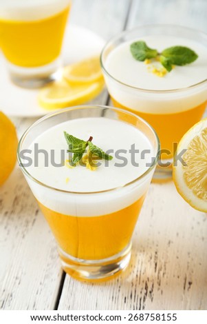 Tasty lemon jelly in glass on white wooden background