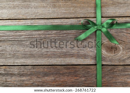 Green ribbon with bow on grey wooden background