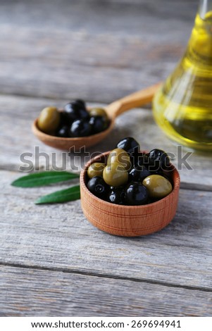 Green and black olives in bowl on grey wooden background
