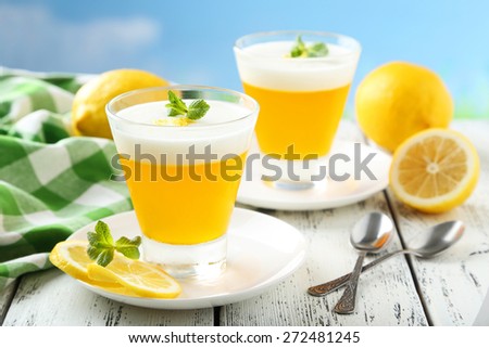 Tasty lemon jelly in glass on white wooden background