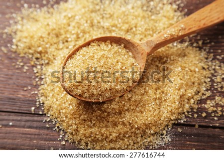 Brown sugar in spoon on brown wooden background