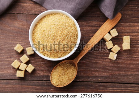 Brown sugar in bowl on brown wooden background
