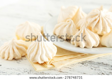 French meringue cookies on plate on white wooden background