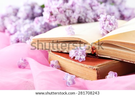 Beautiful lilac flowers with book on pink cloth background