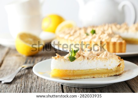Lemon meringue pie on plate on grey wooden background