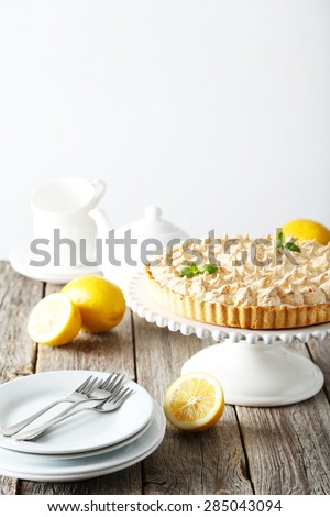 Lemon meringue pie on cake stand on grey wooden background