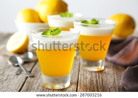Tasty lemon jelly in glass on grey wooden background