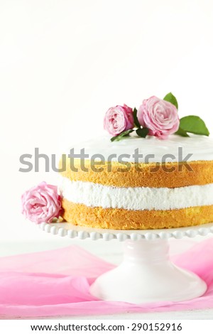 Sweet cake on cake stand on white wooden background