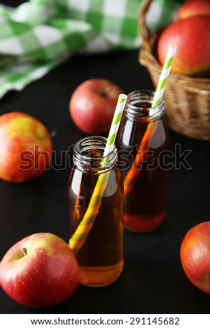 Bottles of apple juice with apples on black background