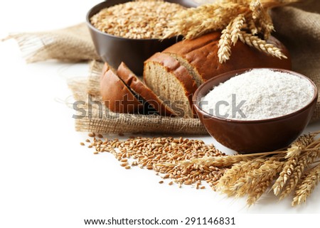 Ears of wheat and bowl of flour and wheat grains on white background