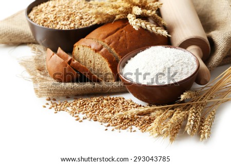 Ears of wheat and bowl of flour and wheat grains on white background