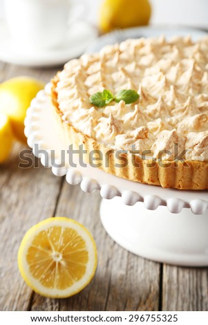 Lemon meringue pie on cake stand on grey wooden background