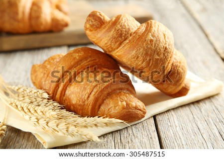 Tasty croissants with spikelets on grey wooden background