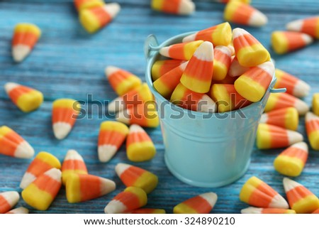 Halloween candy corns in bucket on blue wooden background