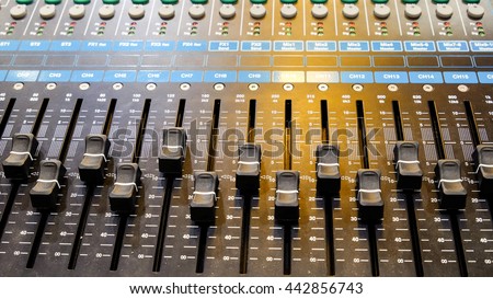 Closeup on a sliders of a mixing console. It is used for audio signals modifications to achieve the desired output. Applied in recording studios, broadcasting, television and film post-production.