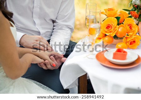 Hands of the newly-married couple embrace each other.