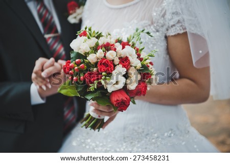 Bouquet in hands of the newly-married couple.